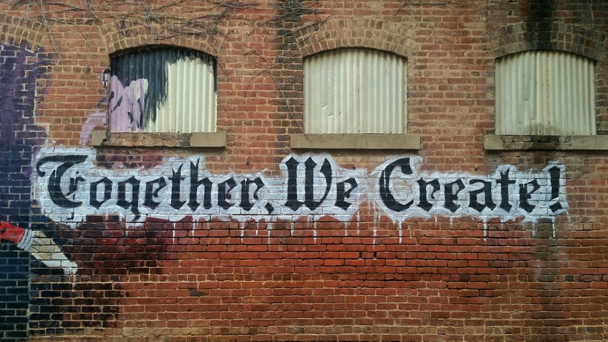 Together We Create! painted in large letters on a brick wall.